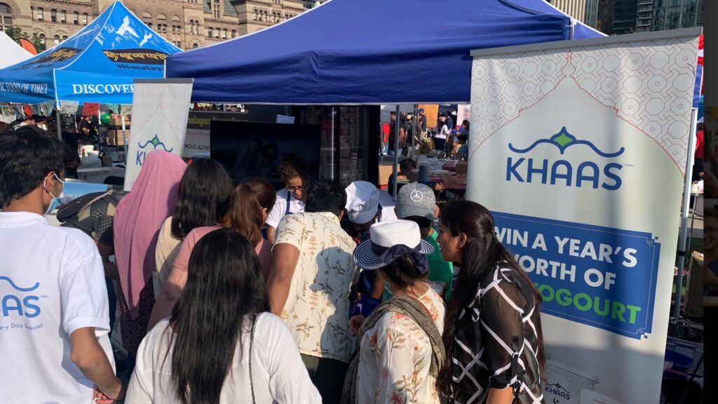 Retail experiential marketing activation at a Canadian outdoor event, with shoppers engaging at a branded food booth, product sampling, and on-ground brand interaction.
