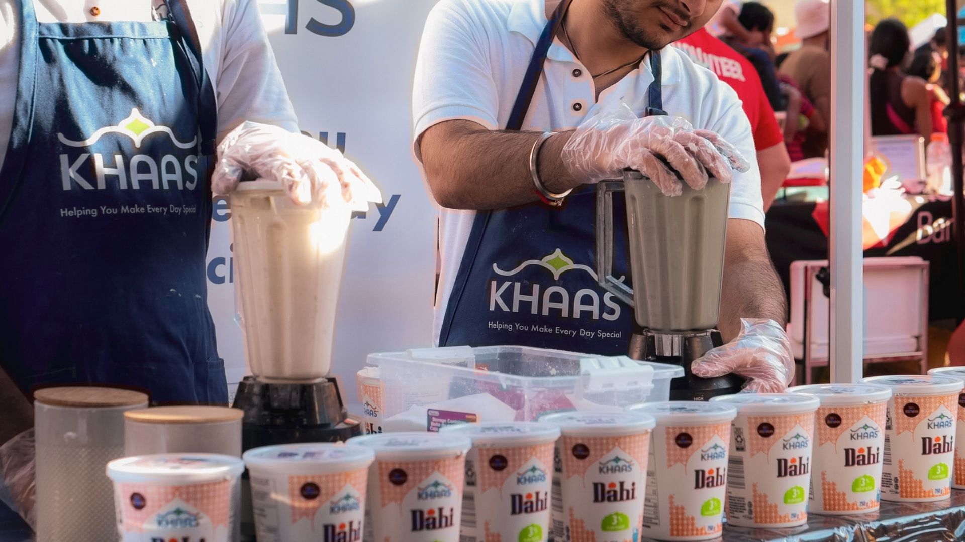 Retail experiential marketing activation featuring live product sampling, with brand ambassadors preparing and demonstrating dairy products at a branded booth.