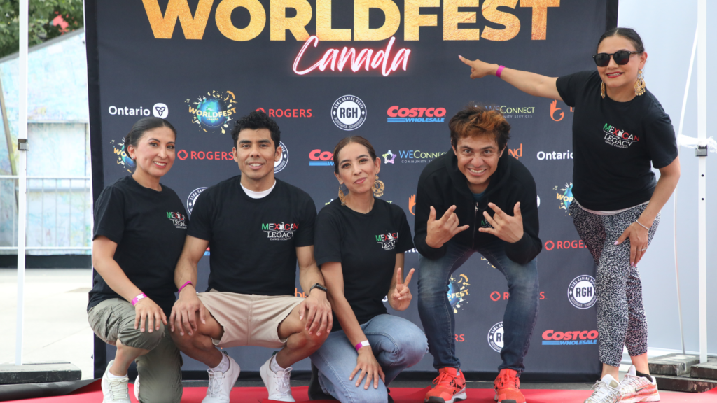 Group posing at WorldFest Canada event backdrop with sponsor logos and branded step-and-repeat display