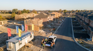 Aerial view of a Greater Toronto Area new-home construction site with townhomes and detached homes under build and a sales centre in the foreground.