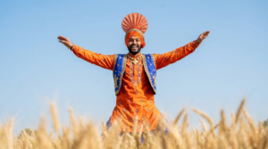 Vaisakhi brand activation Canada 2026: a bhangra dancer mid-leap in traditional Punjabi costume against a bright spring sky in Brampton, Ontario.